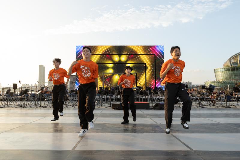 주황색 단체 티를 입고 춤추는 네 명의 사람들 사진