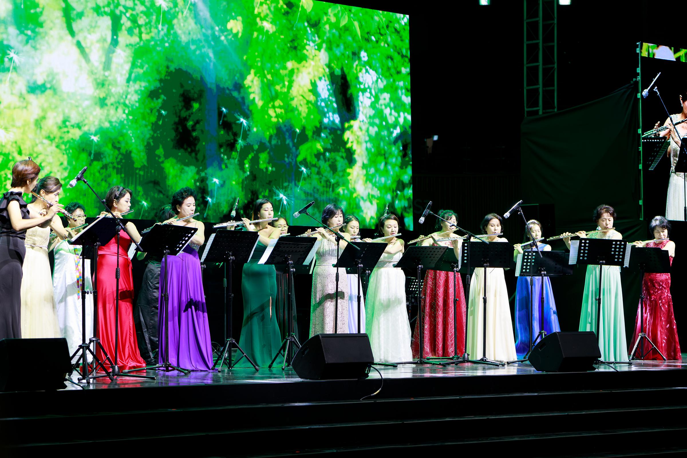 플룻 동호회의 무대 사진.드레스를 입은 다수의 여성으로 이루어져있다.